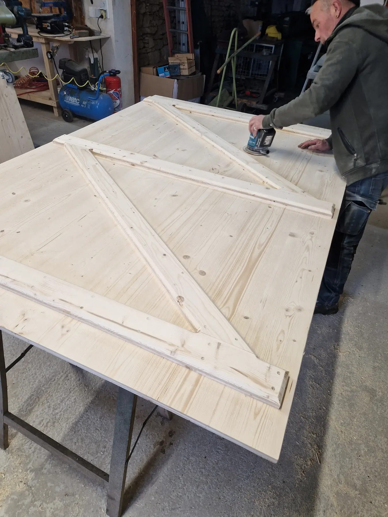 Ponçage d’une grande porte en bois dans l’atelier familial