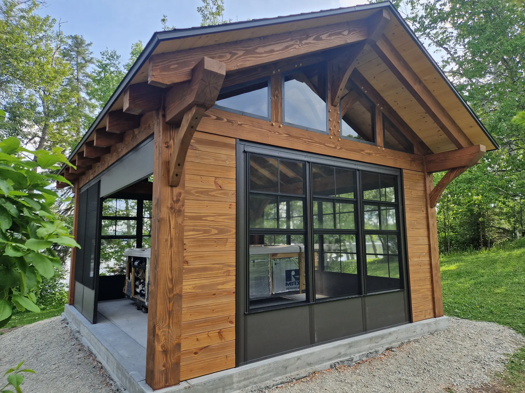 Petite structure en bois massif avec grandes ouvertures vitrées dans un environnement arboré