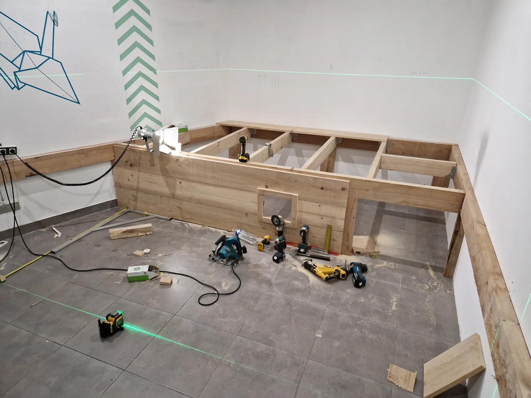 Aménagement intérieur en bois en cours de réalisation avec outils et lignes de niveau