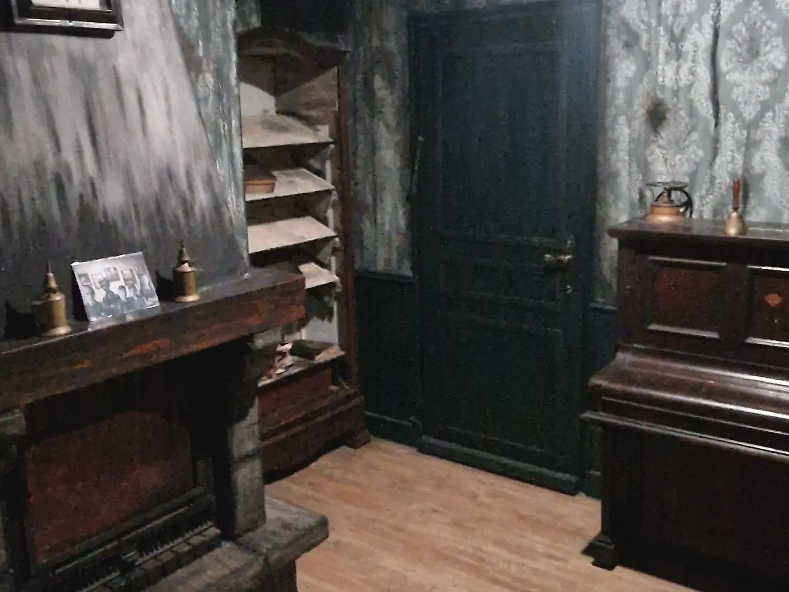 Décor d’escape game terminé avec cheminée, piano, porte sombre et murs patinés